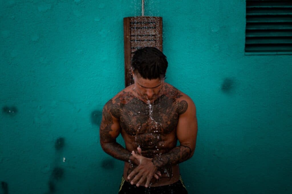 Man with tattoos showering outdoors