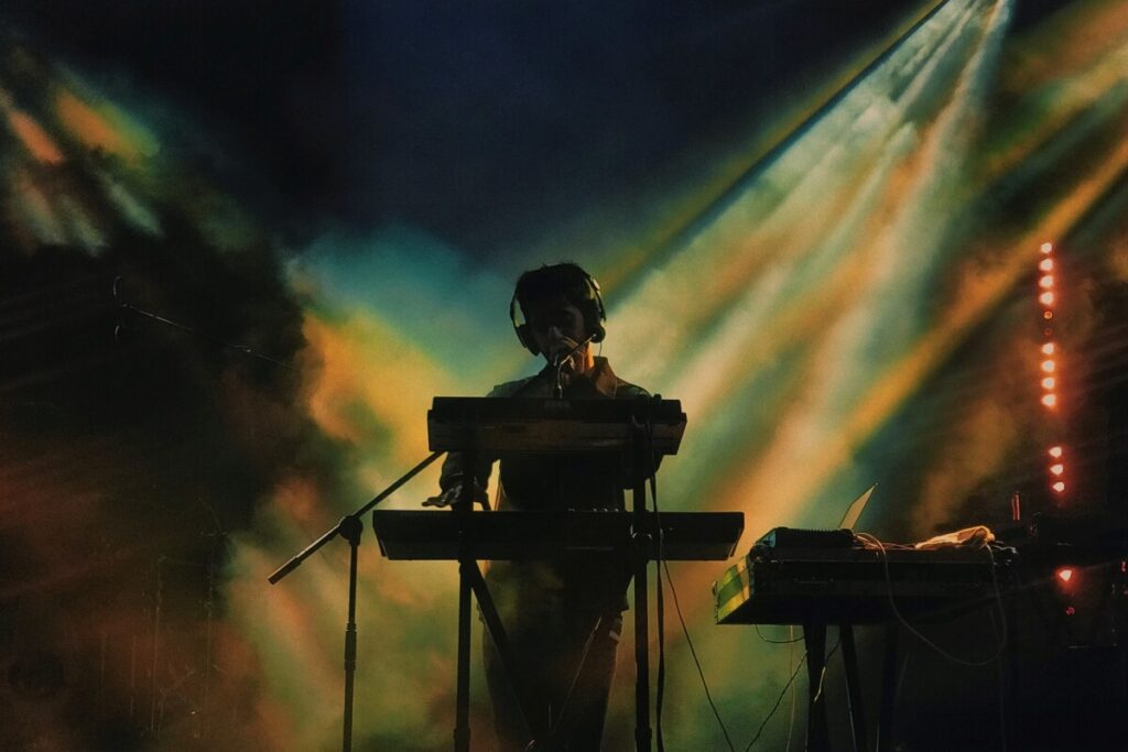 Silhouette of man playing keyboard on stage at concert