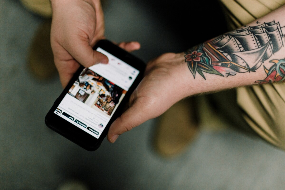 Man with tattoos scrolling social media