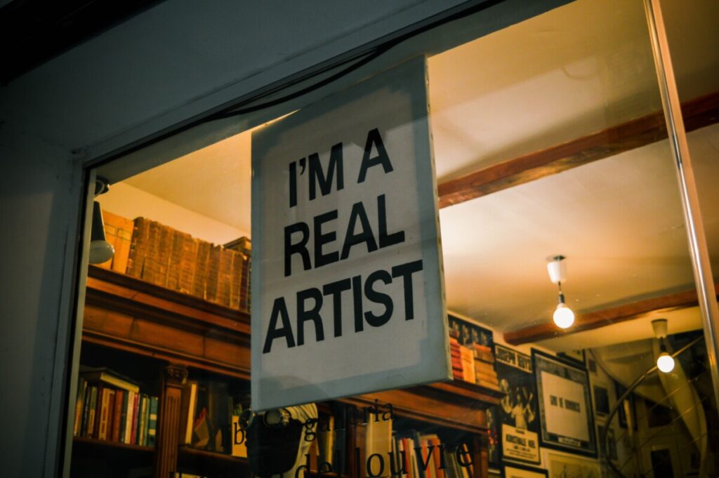 A sign in a shop window that reads, "I'm a real artist".