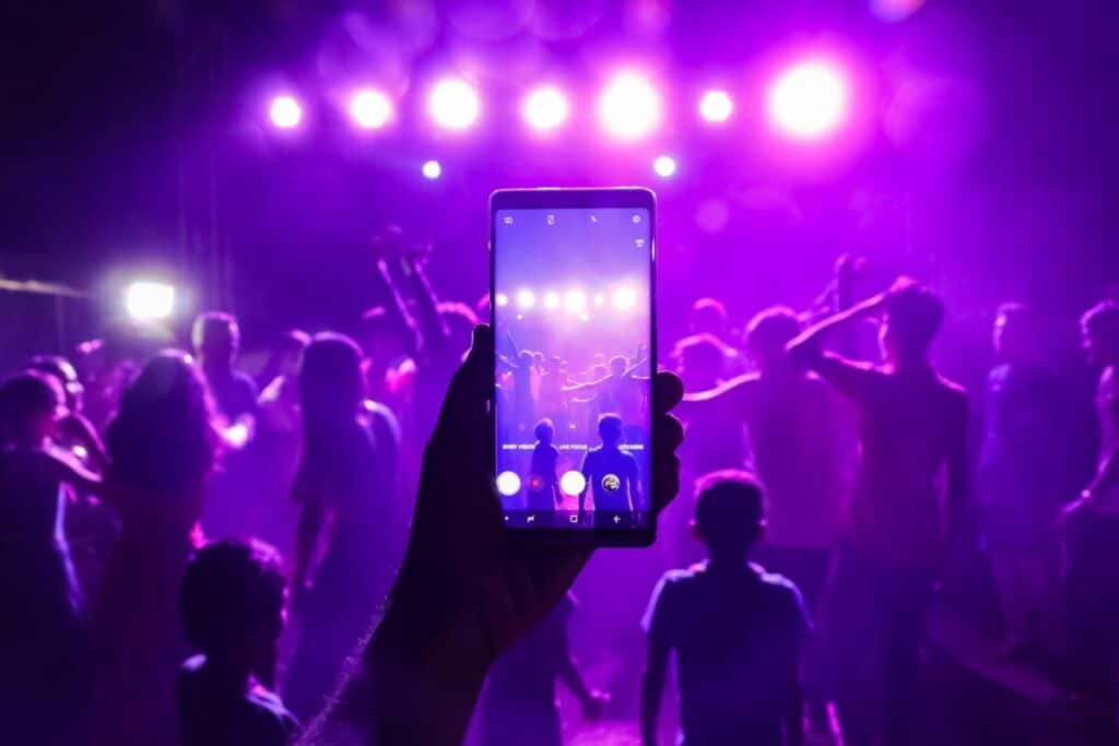 A hand holding a phone at  a concert