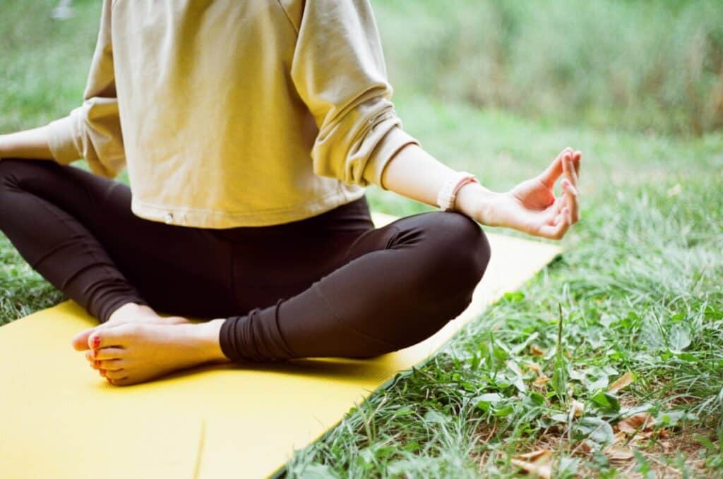 Person meditating on a yellow yoga mat