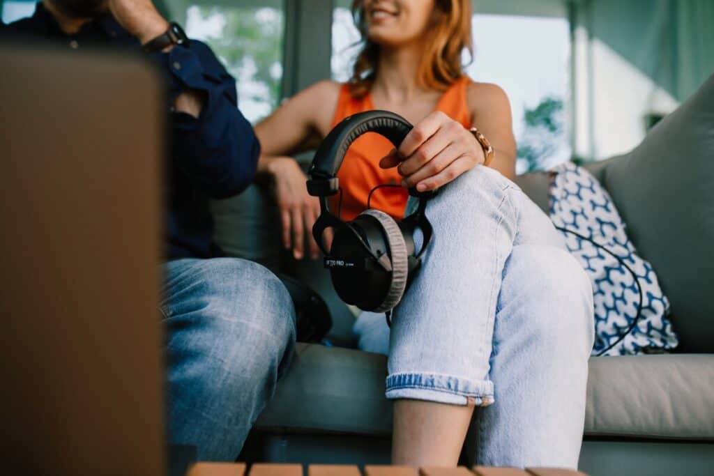 Man and woman sitting on a couch holding headphones