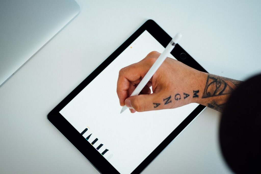 Hand with tattoos writing on a tablet